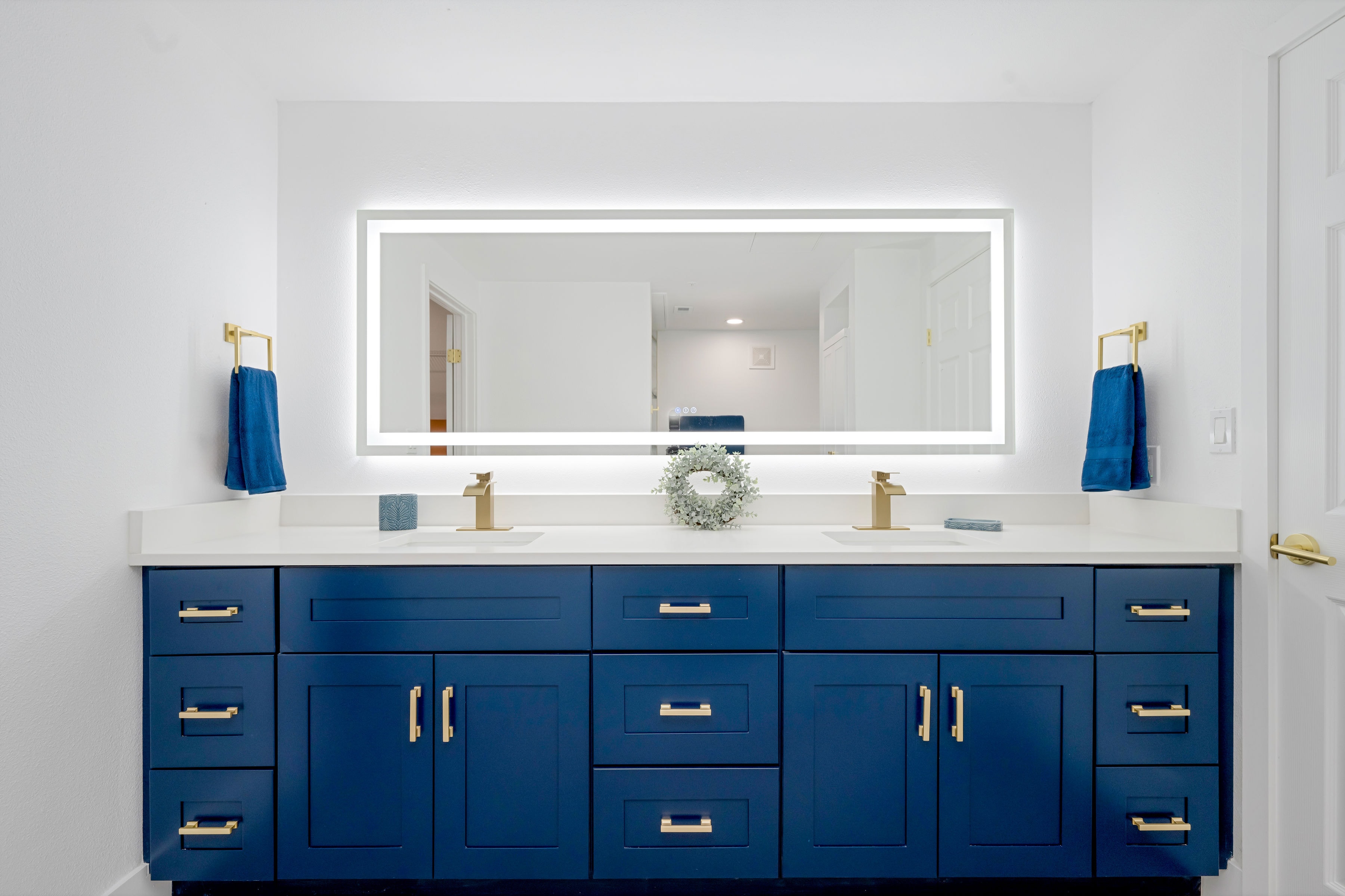 Navy double vanity with gold hardware and backlit LED mirror
