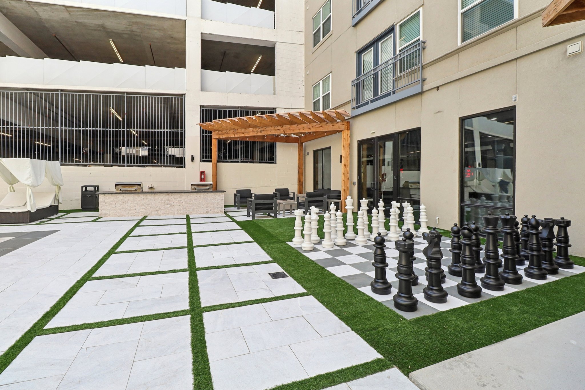 Outdoor courtyard with giant chess set, pergola, and grilling station