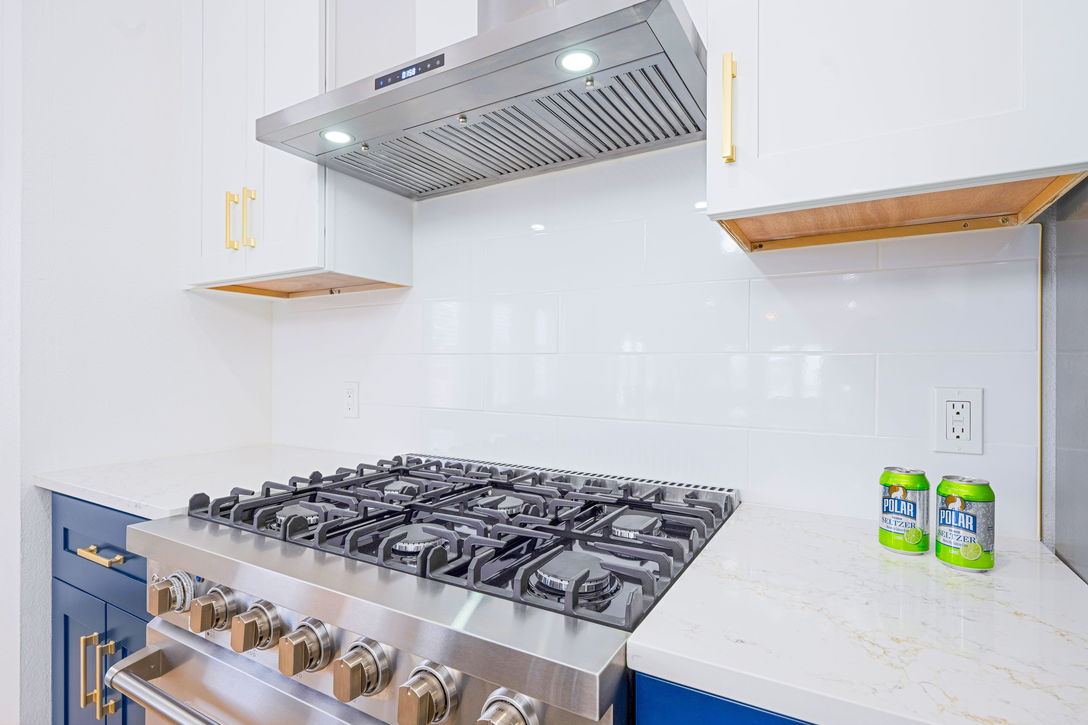 Professional gas range with stainless hood, white cabinets and gold hardware