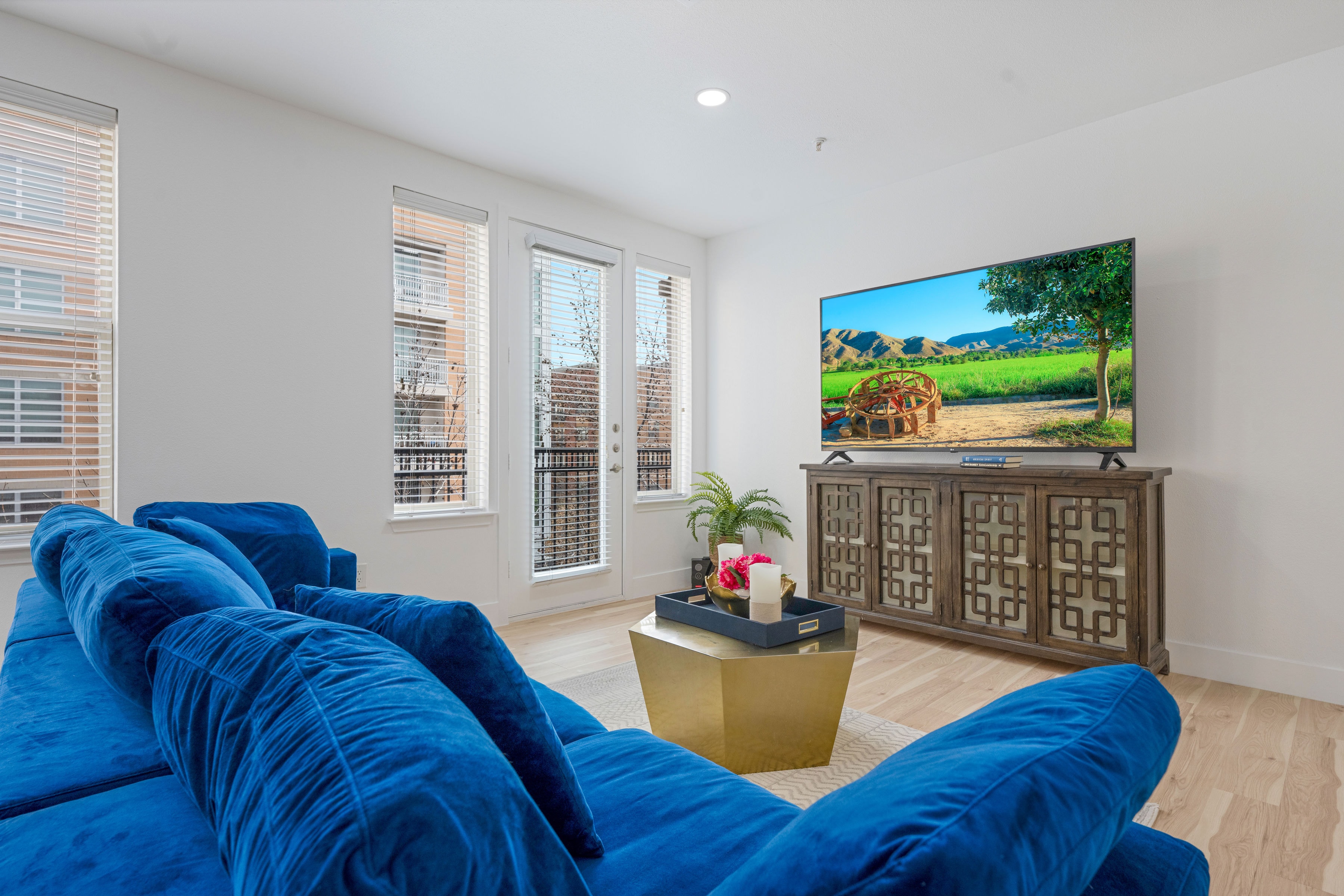 Living room with blue velvet sofa, gold coffee table, and large TV