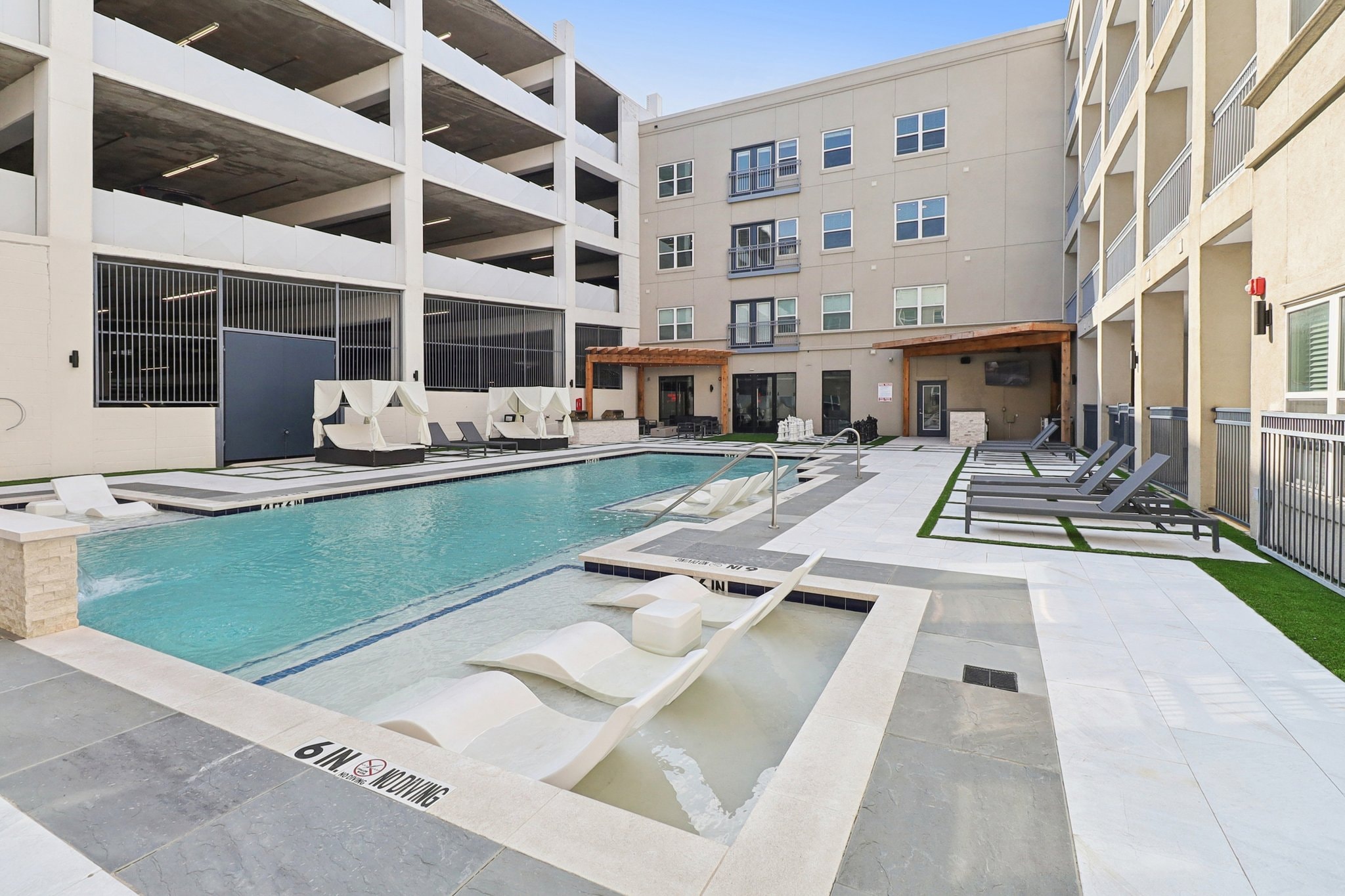 Pool with in-water loungers, spa, and pergola seating area