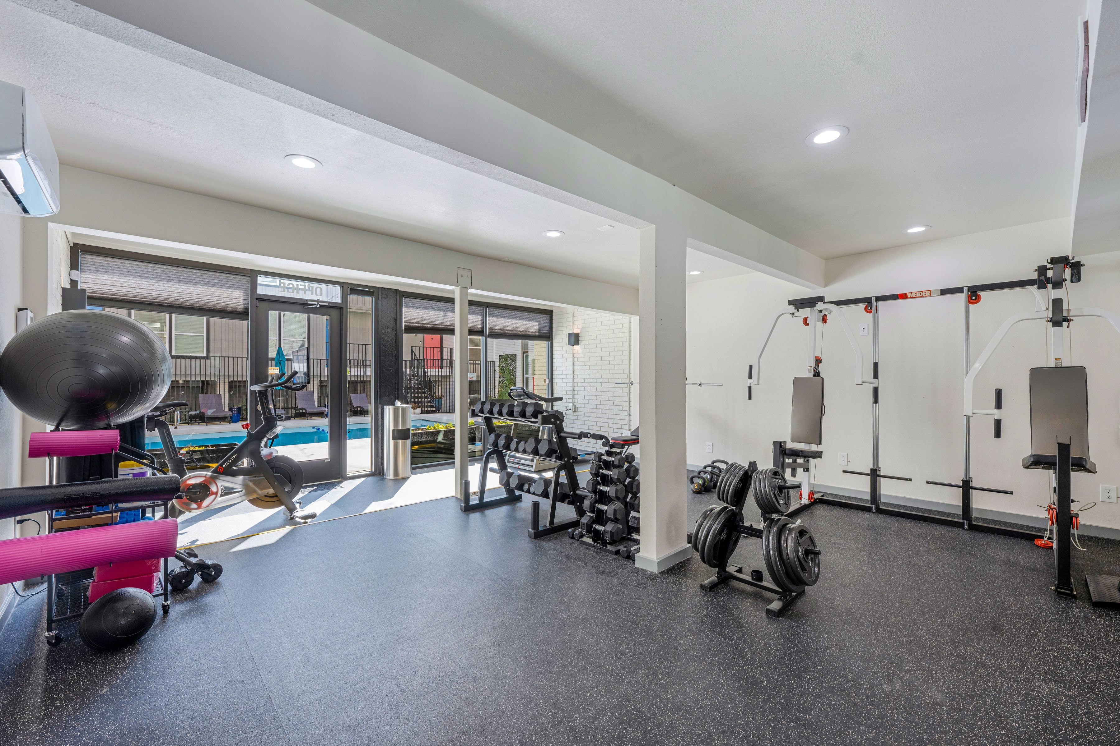 Fitness center with weights, Peloton bike, and pool view