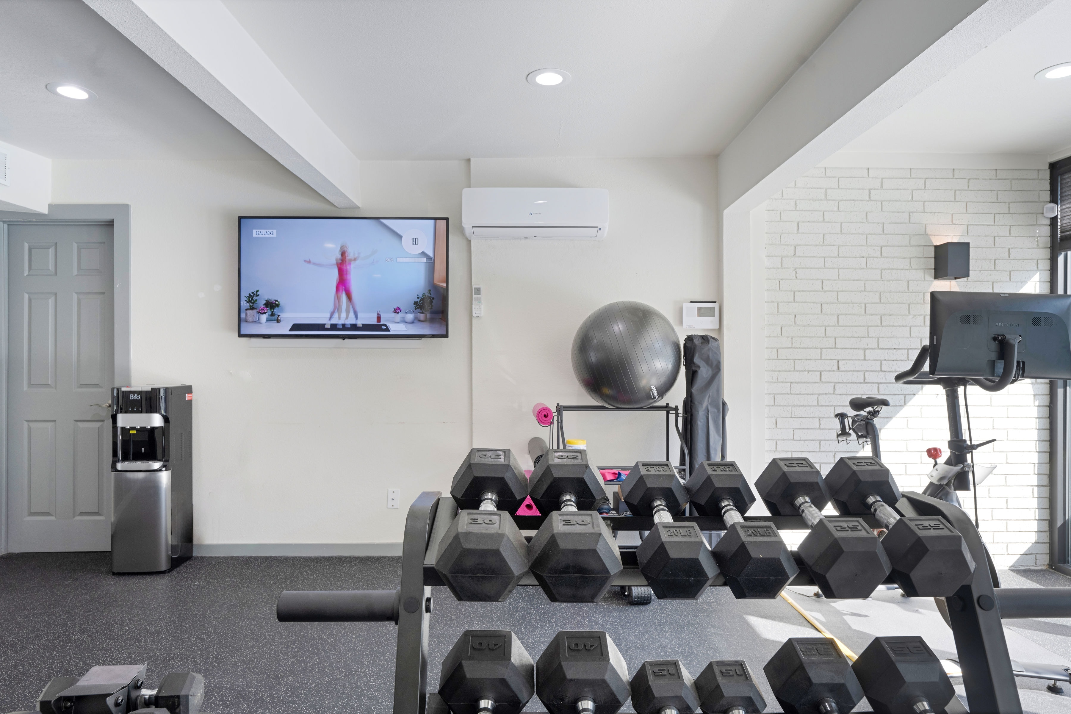 Fitness center with dumbbells, TV, and Peloton bike