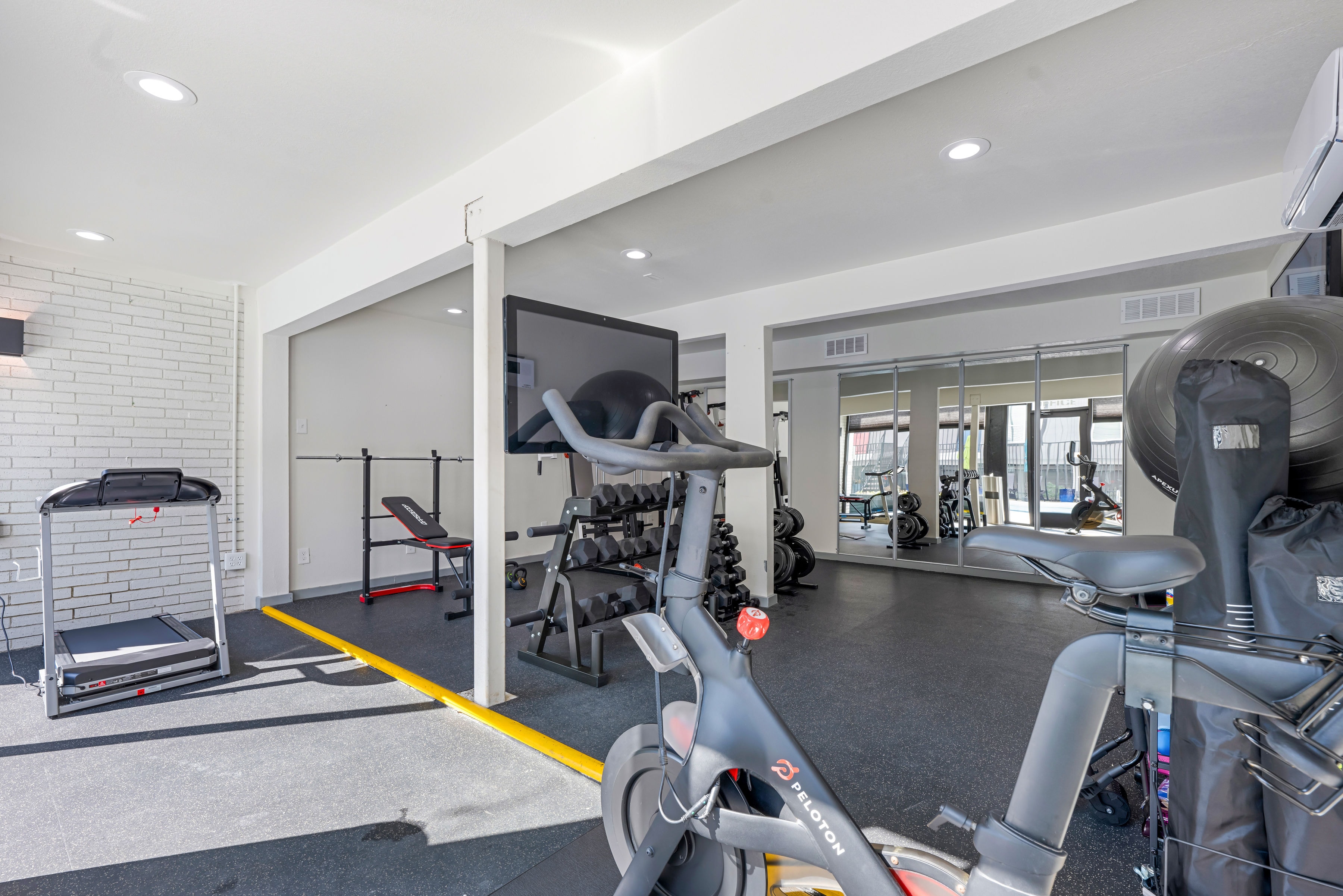 Fitness center with treadmill, weight bench, and mirrored wall