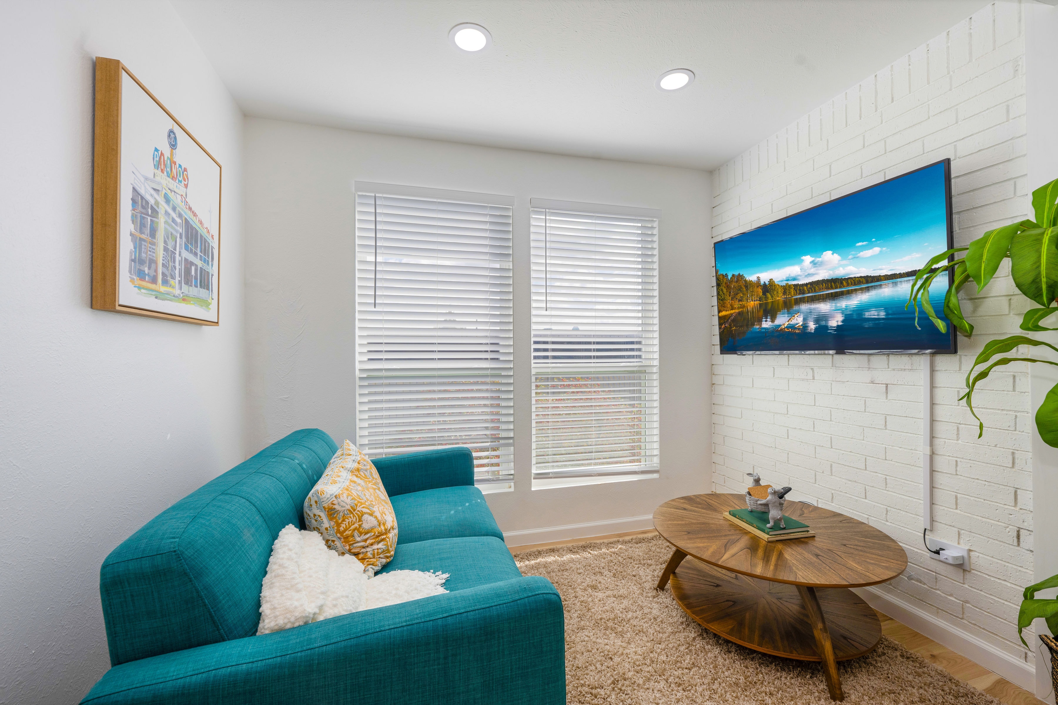 Living room with teal sofa and white brick wall TV