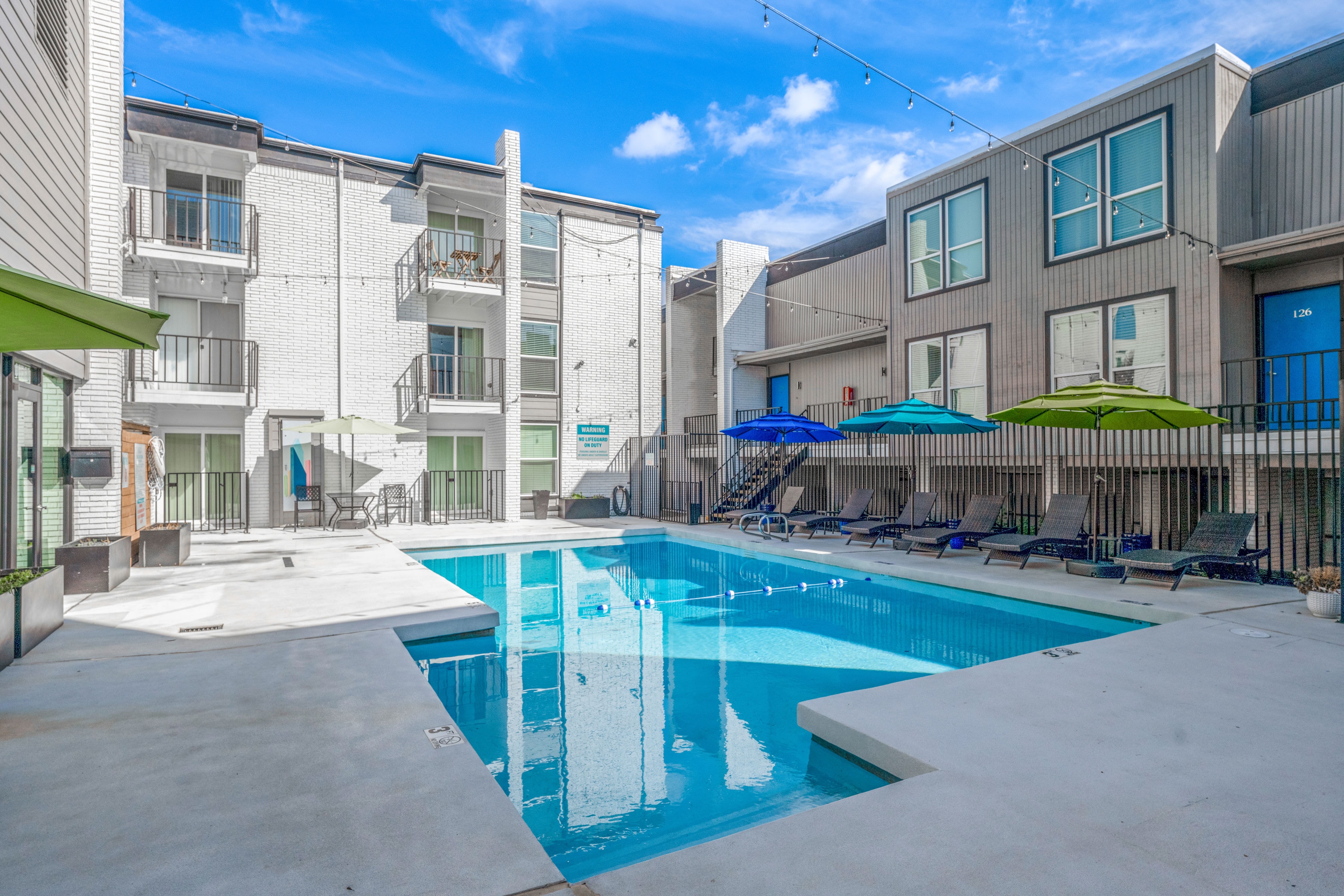 Resort-style pool with lounge chairs and colorful umbrellas