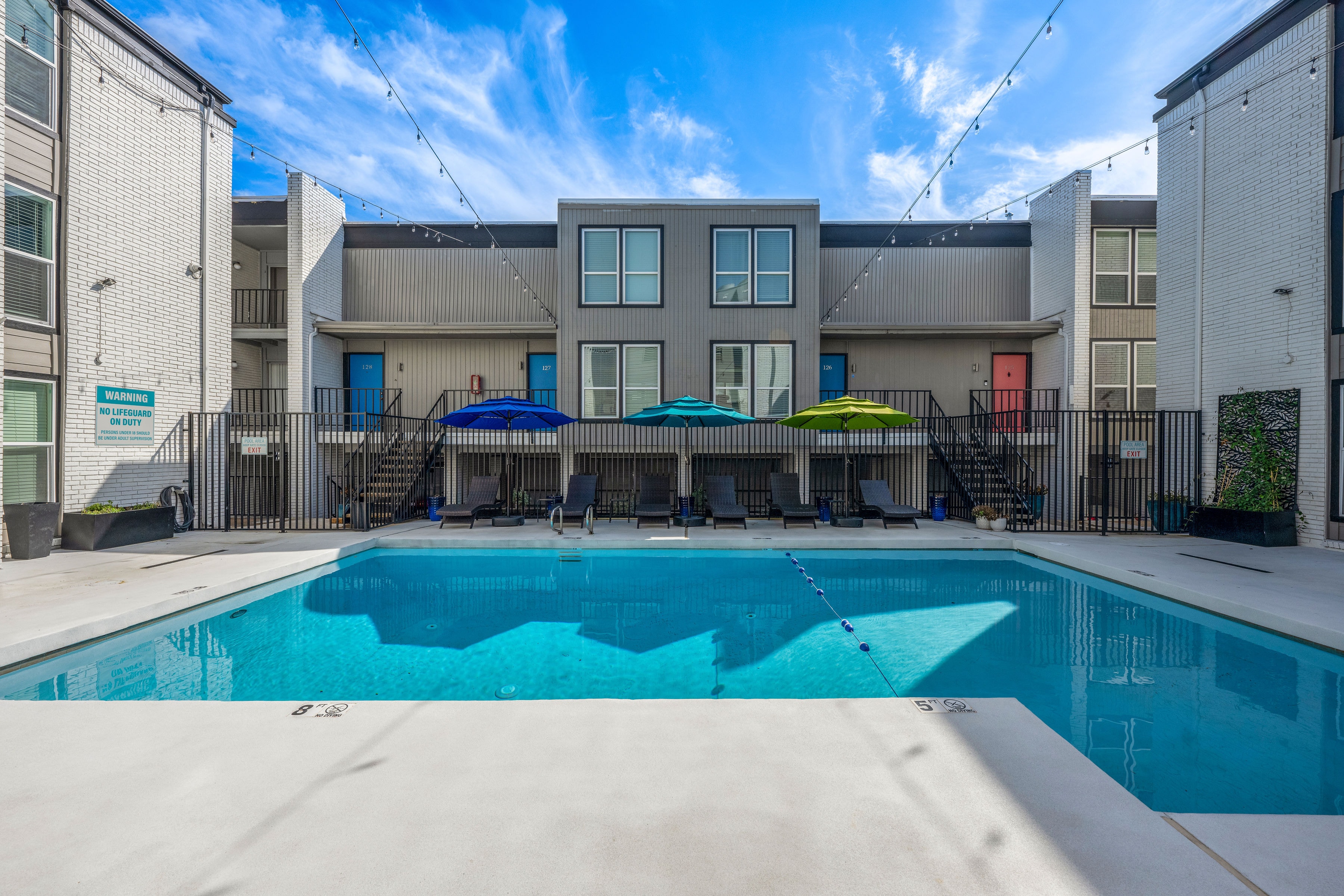 Pool with lounge chairs and colorful unit doors